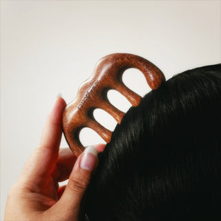 Wooden gua sha beging run through black hair