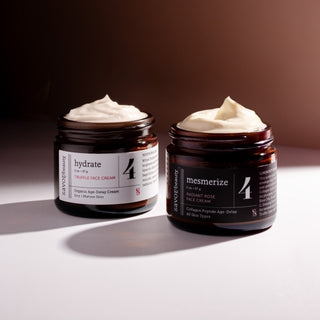 Two jars of face cream labeled 'hydrate' and 'mesmerize' on a gradient background