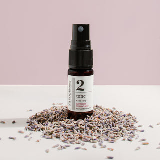 Bottle of '2 tone' product surrounded by lavender flowers on a light background
