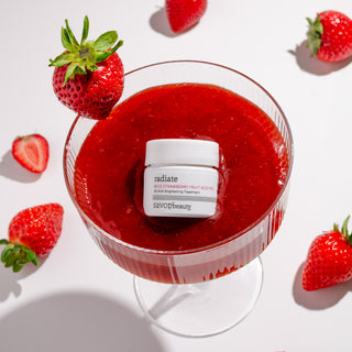 White jar of skincare floating in pink strawberry face peel