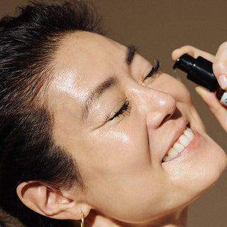 Woman applying a skincare product to her face with a neutral background