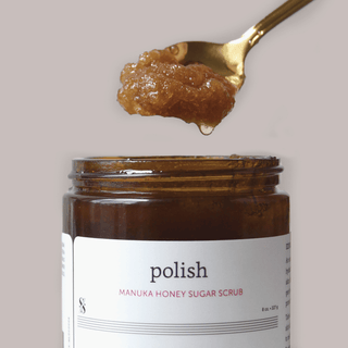 Manuka Honey Sugar body Scrub open jar scooping with golden spoon
