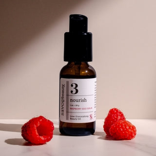 Bottle of Raspberry Seed Serum with 3 raspberries on a neutral background