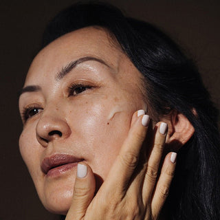 Woman applying a swatch of Jasmine Milk Cleansing Milk to face.