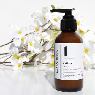 Jasmine Milk Cleanser bottle standing with flowers in the background.